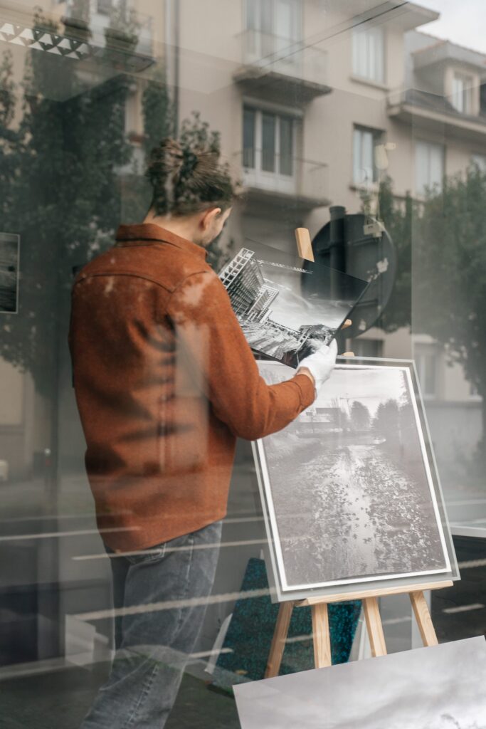 Jérémy Fruchaud installant des tirages photographiques en vitrine de l'atelier Sel de Pixel rue Saint-Hélier à Rennes.